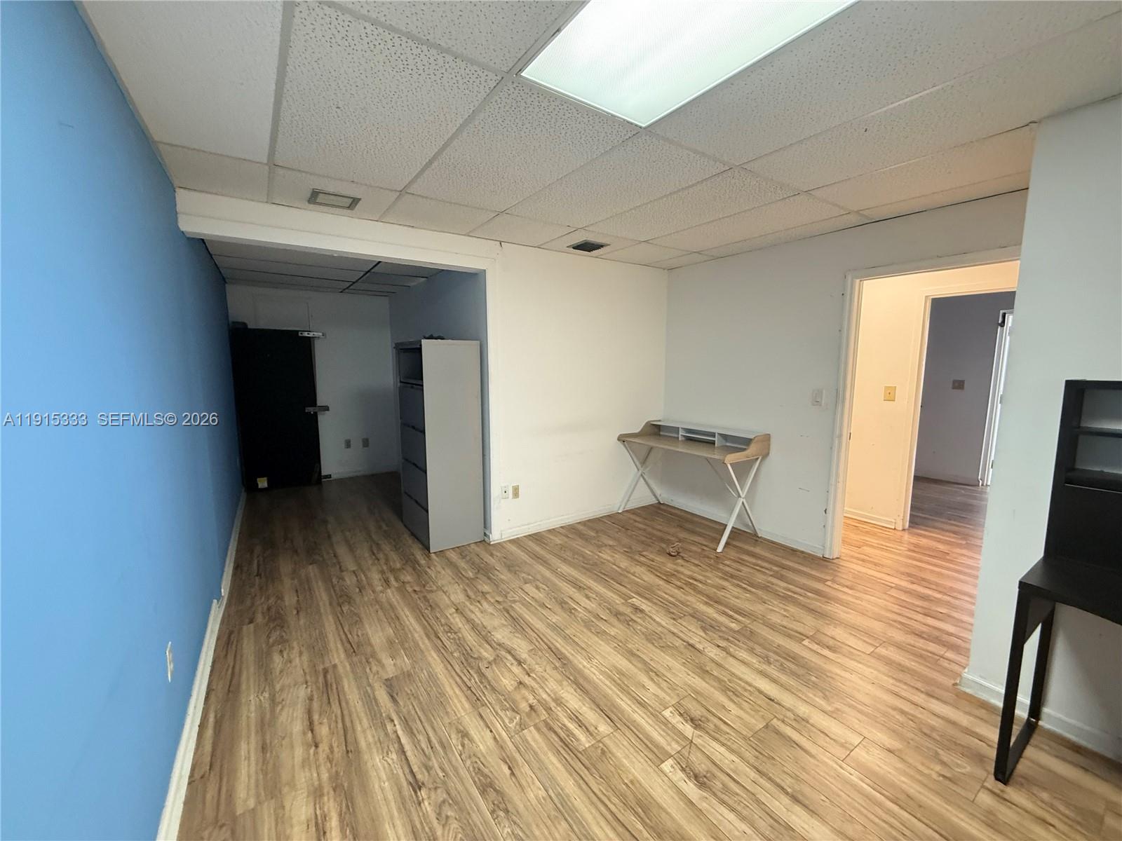 An office space features wood-look flooring, a blue accent wall, and a drop ceiling — 8000 NW 31st St # 19, Doral FL 33122, DORAL, FL