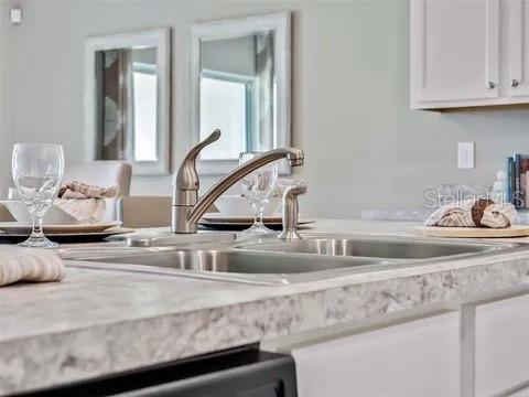 A kitchen sink with a stainless steel faucet sits on a light-colored countertop — 679 MADRID DRIVE, KISSIMMEE, FL