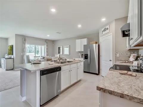 A modern kitchen features white cabinets, stainless steel appliances, and an island with a dishwasher — 679 MADRID DRIVE, KISSIMMEE, FL