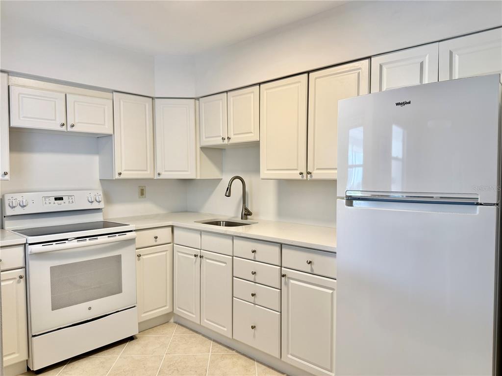 A kitchen with white cabinets, white appliances, and light-colored countertops — 2221 ORANGE BLOSSOM LANE, BRADENTON, FL