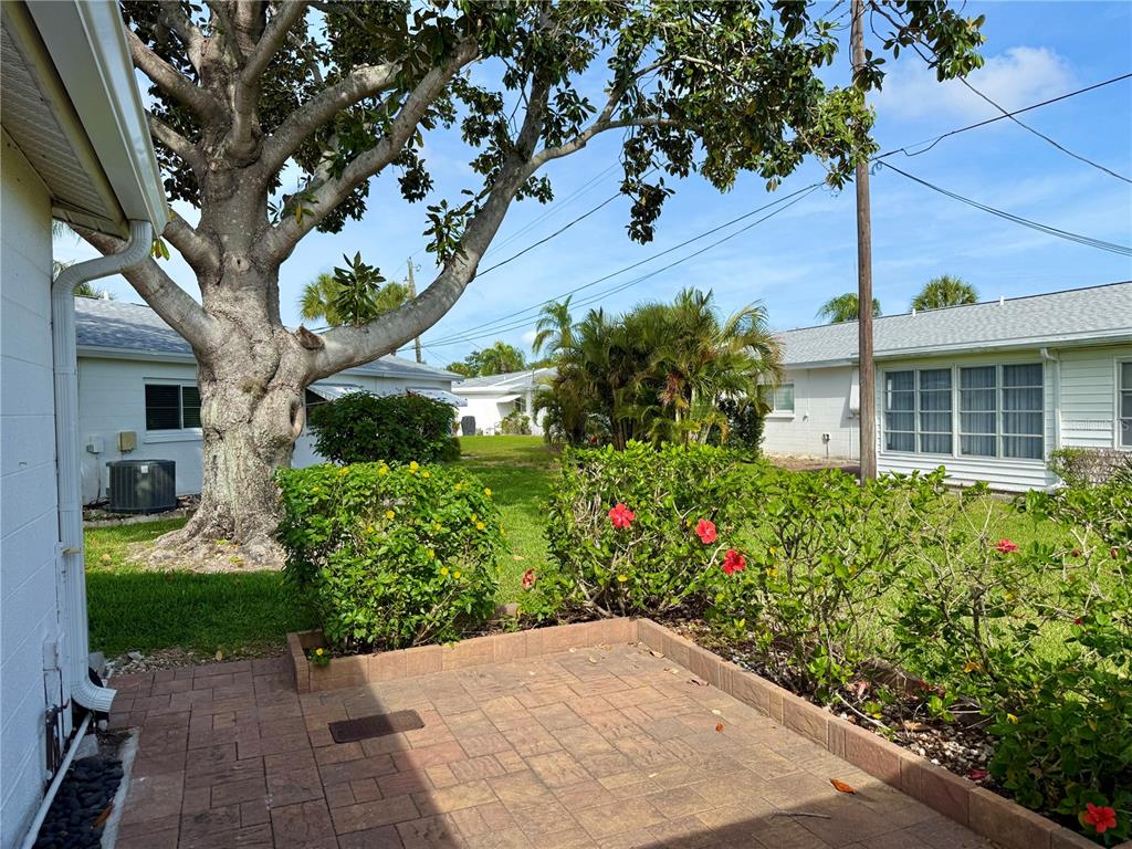 A paved patio sits in front of a landscaped yard with a large tree — 2221 ORANGE BLOSSOM LANE, BRADENTON, FL