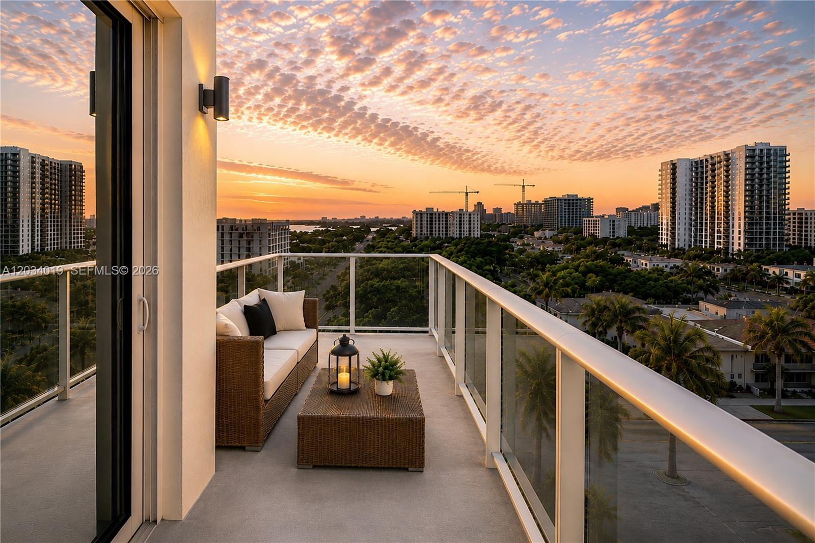 A balcony with wicker furniture overlooks a city skyline at sunset — 321 NE 26th St # 806, Miami FL 33137, MIAMI, FL