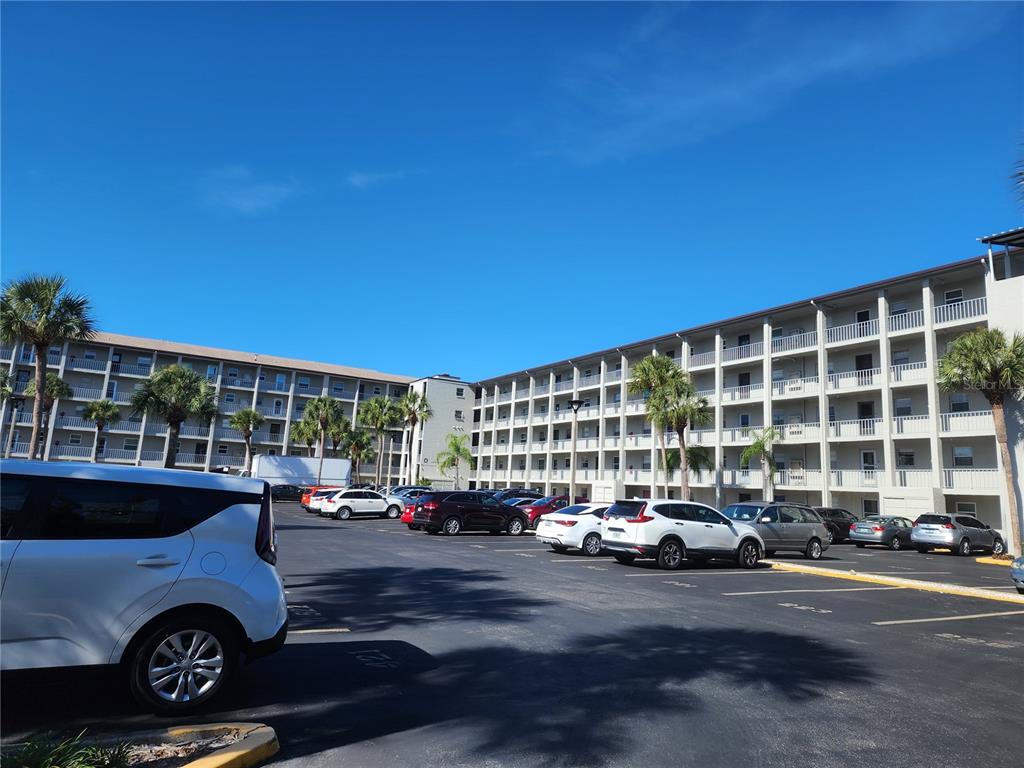 A multi-story apartment building with exterior walkways overlooks a parking lot filled with cars — 3064 LAKE BAYSHORE DRIVE UNIT 115, BRADENTON, FL