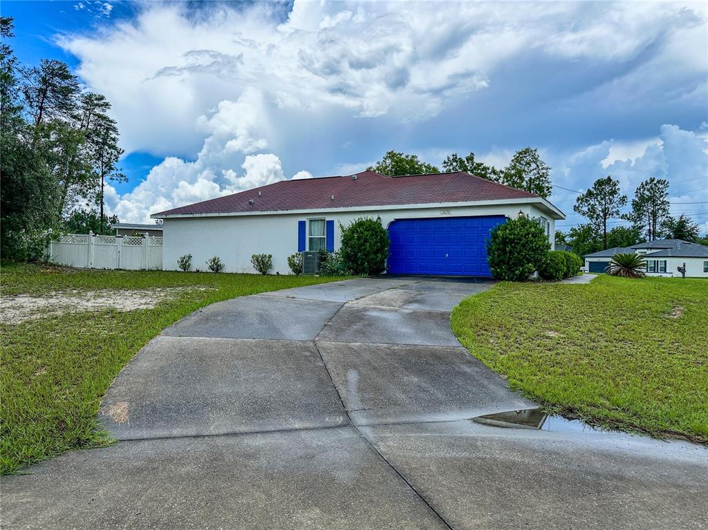 A single-story house with a white exterior, red roof, and a blue garage door — 13076 SW 78TH TERRACE, OCALA, FL
