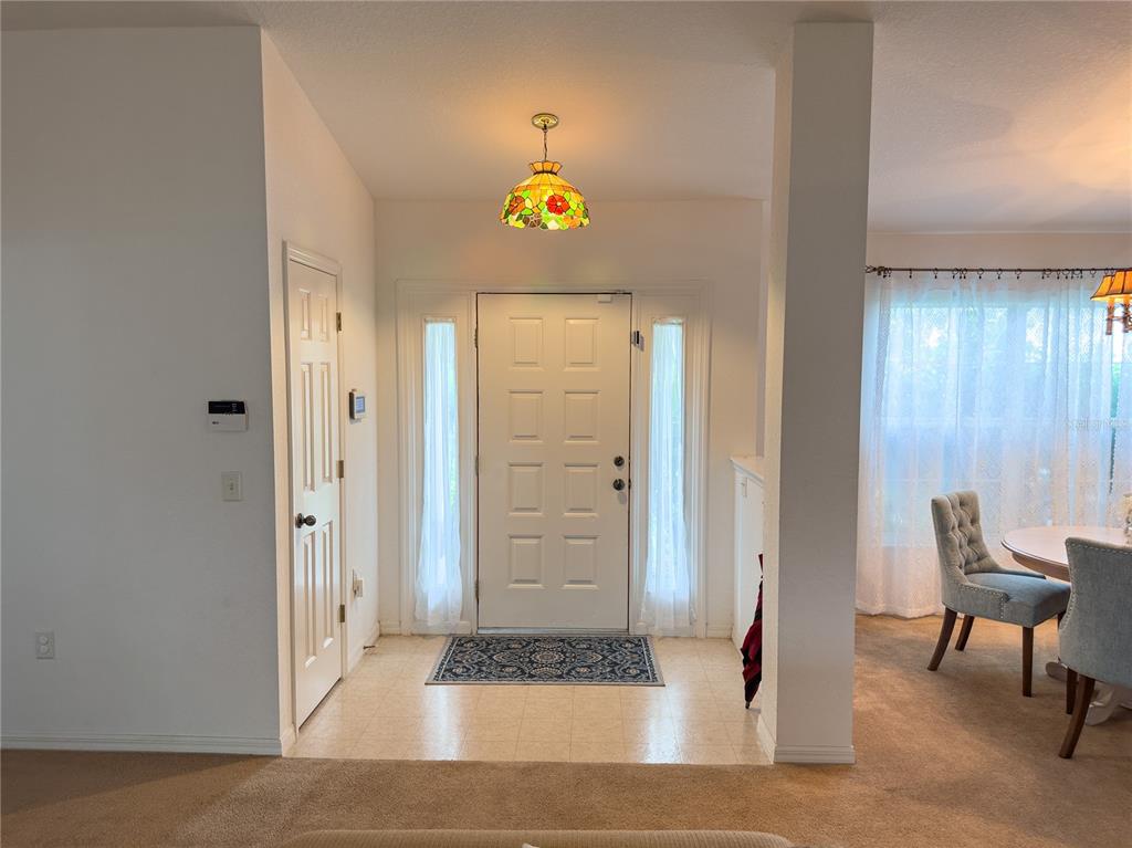 An entryway features a white front door with sidelights, a stained-glass pendant light, and tile — 13076 SW 78TH TERRACE, OCALA, FL