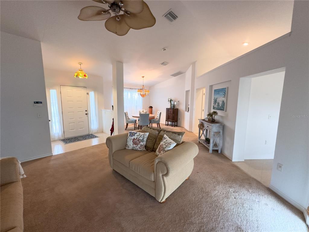 A living room with beige carpet and a sofa leads to a dining area — 13076 SW 78TH TERRACE, OCALA, FL