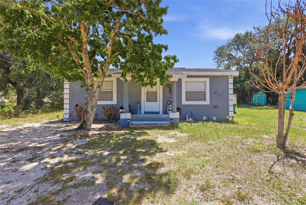 A gray, single-story house with a front porch, white trim, and a large tree — 2559 HARRY T MOORE AVENUE, MIMS, FL