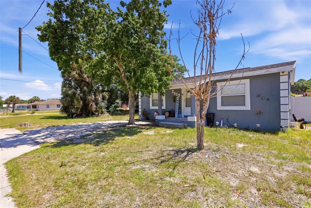A gray single-story house with a front porch and a large tree in the yard — 2559 HARRY T MOORE AVENUE, MIMS, FL