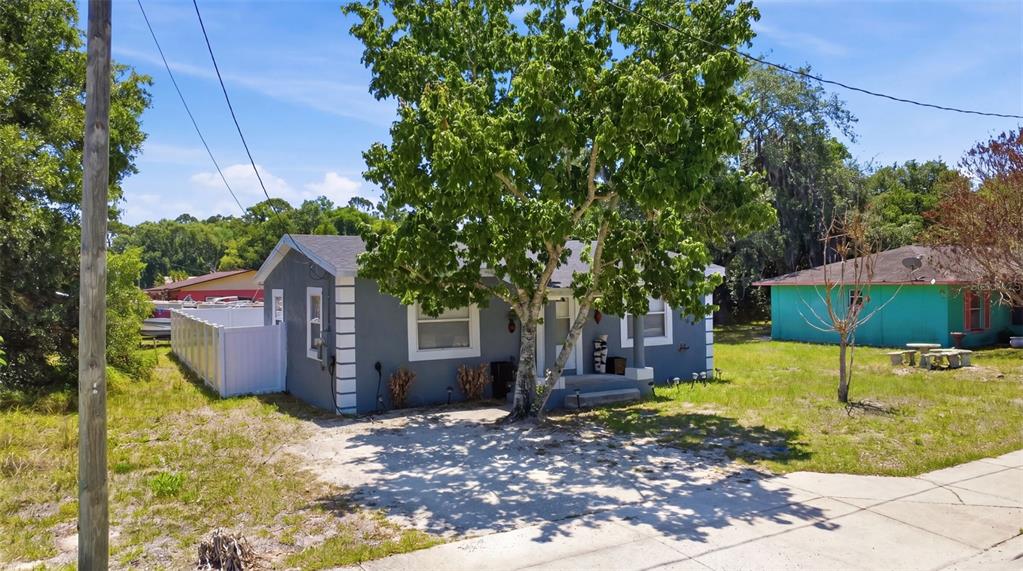 A gray single-story house with white trim and a large tree in the front yard — 2559 HARRY T MOORE AVENUE, MIMS, FL
