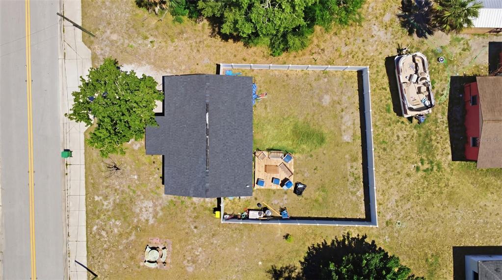 An aerial view shows a house with a fenced backyard, a wooden deck, and a boat — 2559 HARRY T MOORE AVENUE, MIMS, FL