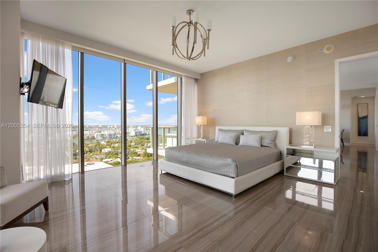 A modern bedroom features floor-to-ceiling windows, a white platform bed, and polished tile flooring — 9705 Collins Ave # 1805N, Bal Harbour FL 33154, BAL HARBOUR, FL