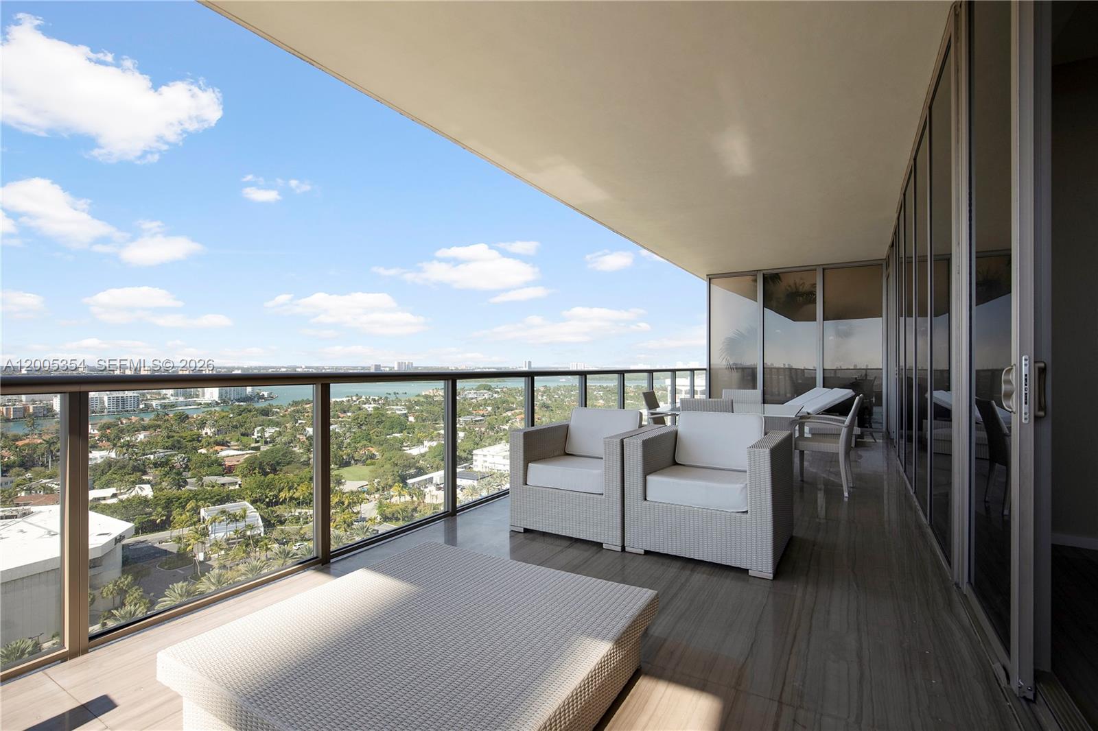 A balcony with outdoor furniture overlooks a city and water view under a blue sky — 9705 Collins Ave # 1805N, Bal Harbour FL 33154, BAL HARBOUR, FL