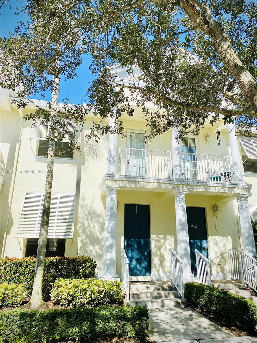 A two-story townhouse exterior features yellow stucco walls, white columns, and dark blue doors — 1557 Frederick Small Rd # 1557, Jupiter FL 33458, JUPITER, FL
