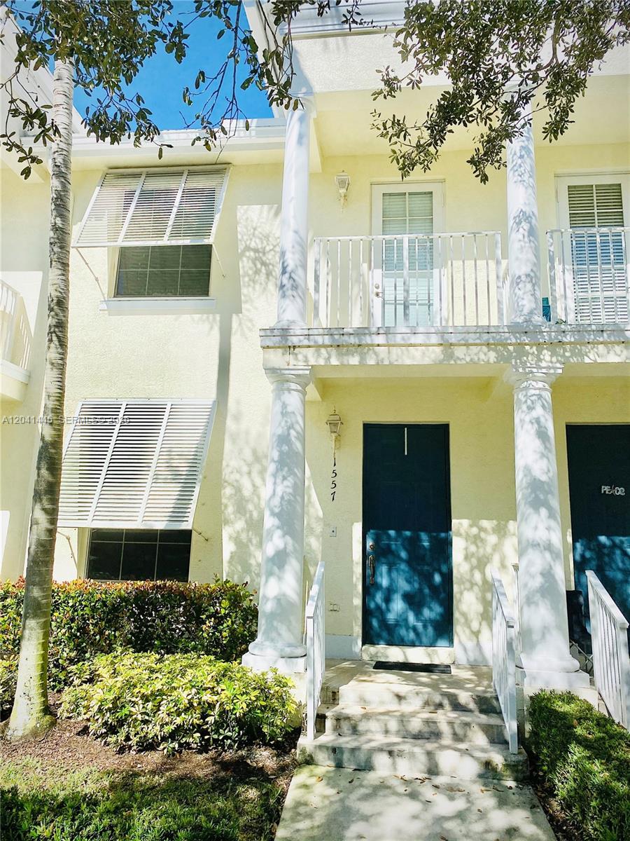A two-story townhouse exterior features a blue front door, white columns, and a small balcony — 1557 Frederick Small Rd # 1557, Jupiter FL 33458, JUPITER, FL