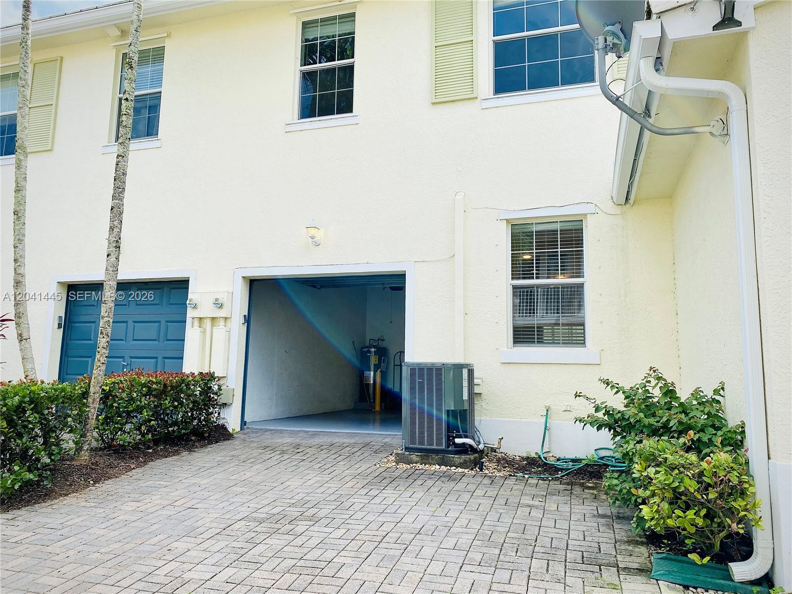 A two-story building exterior features a garage, an HVAC unit, and a paved driveway — 1557 Frederick Small Rd # 1557, Jupiter FL 33458, JUPITER, FL