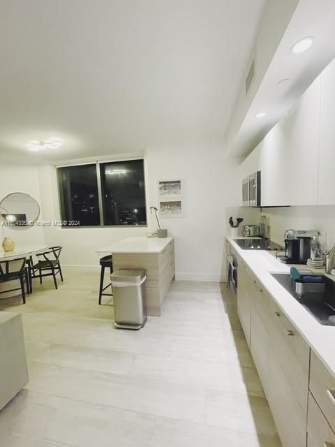 A modern kitchen features light wood cabinetry, white countertops, and an adjacent dining area — 121 NE 34th St # 1409, Miami FL 33137, MIAMI, FL