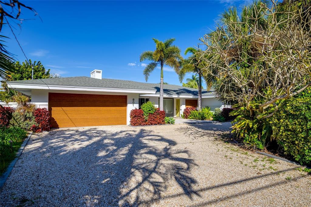 A single-story house with a gravel driveway, palm trees, and landscaping under a blue sky — 801 PINELLAS POINT DRIVE S, ST PETERSBURG, FL
