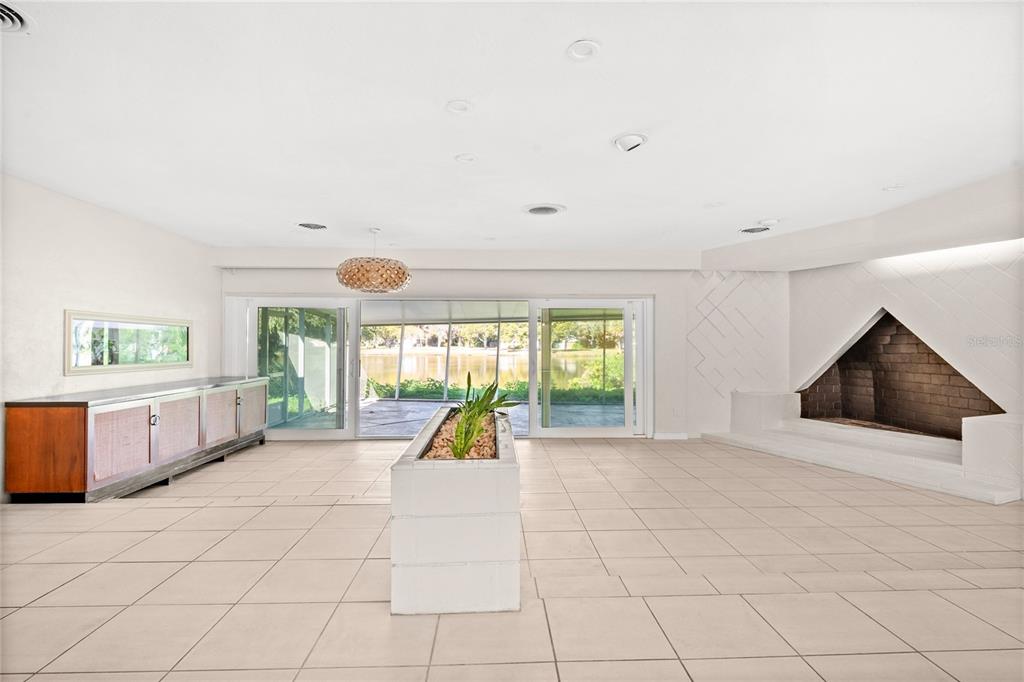 A spacious living room features light tile floors, a unique fireplace, and sliding glass doors — 801 PINELLAS POINT DRIVE S, ST PETERSBURG, FL
