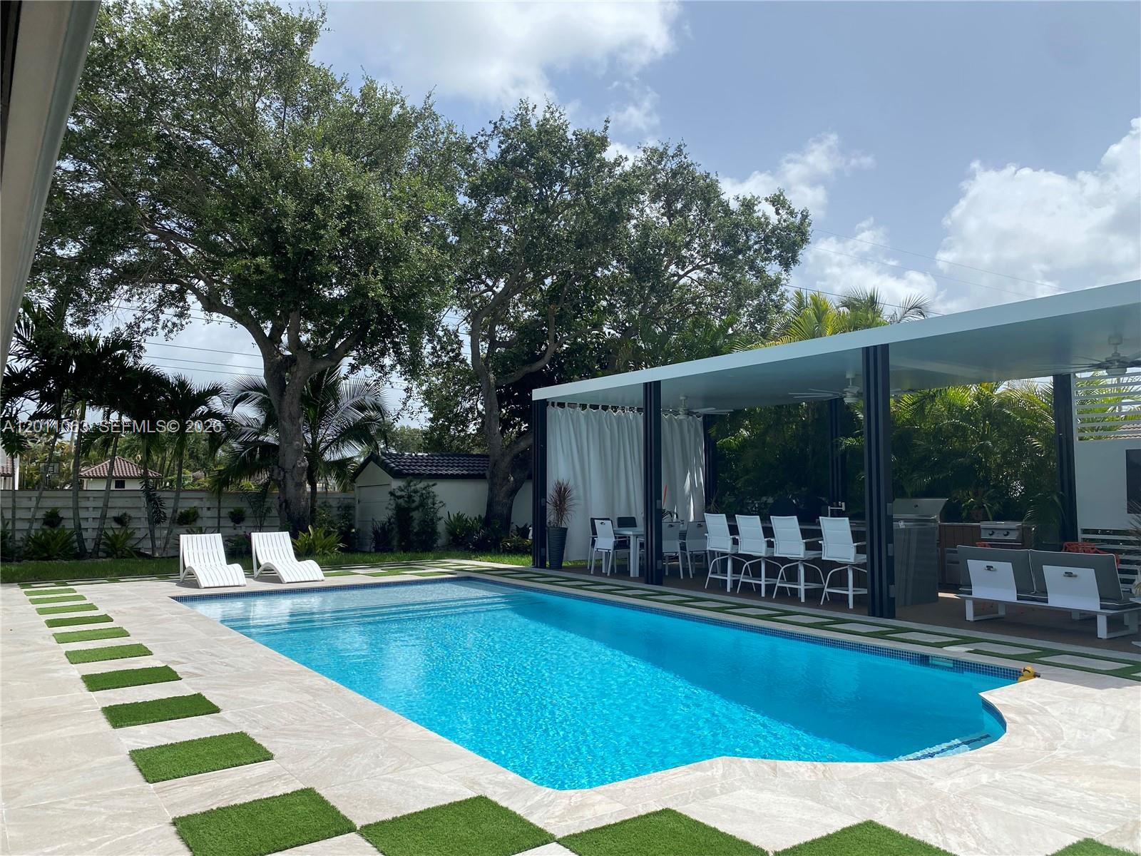A swimming pool with a patio and a covered outdoor kitchen area in a backyard — 13255 SW 106th Ave, Miami FL 33176, MIAMI, FL