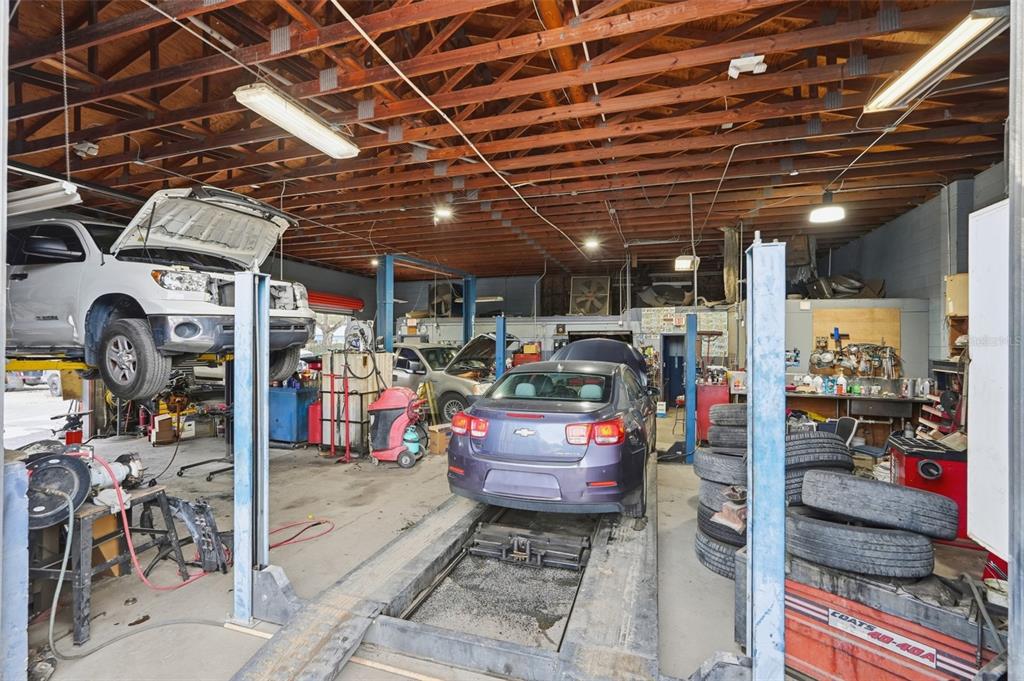 An auto repair shop interior features two vehicles on lifts, tools, and stacked tires — 6512 OLD CHENEY HIGHWAY, ORLANDO, FL