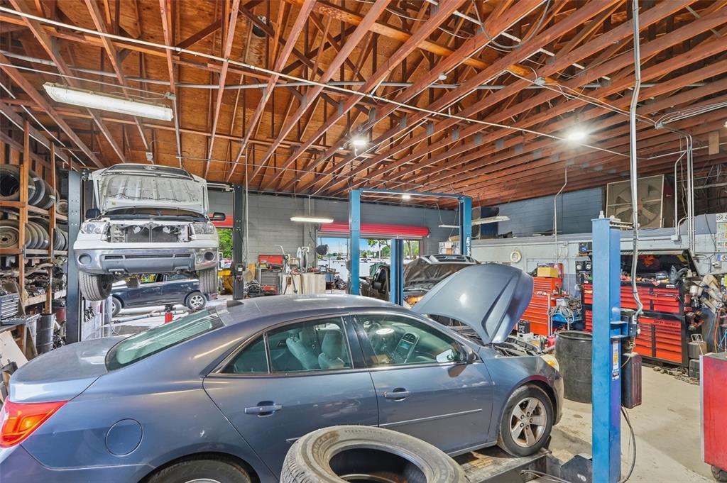 An auto repair shop interior featuring two vehicle lifts, a blue sedan, and exposed rafters — 6512 OLD CHENEY HIGHWAY, ORLANDO, FL