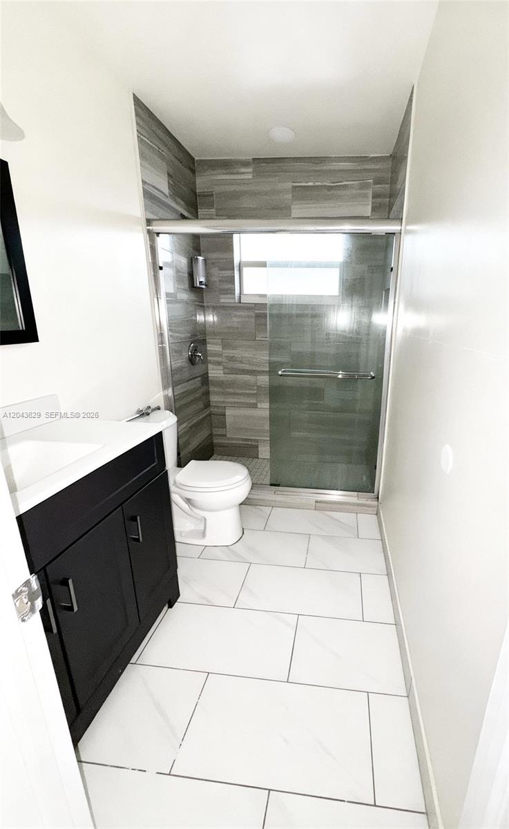 A bathroom features a black vanity, a white toilet, and a glass-enclosed walk-in shower — 5912 Fillmore St # 2, Hollywood FL 33021, HOLLYWOOD, FL