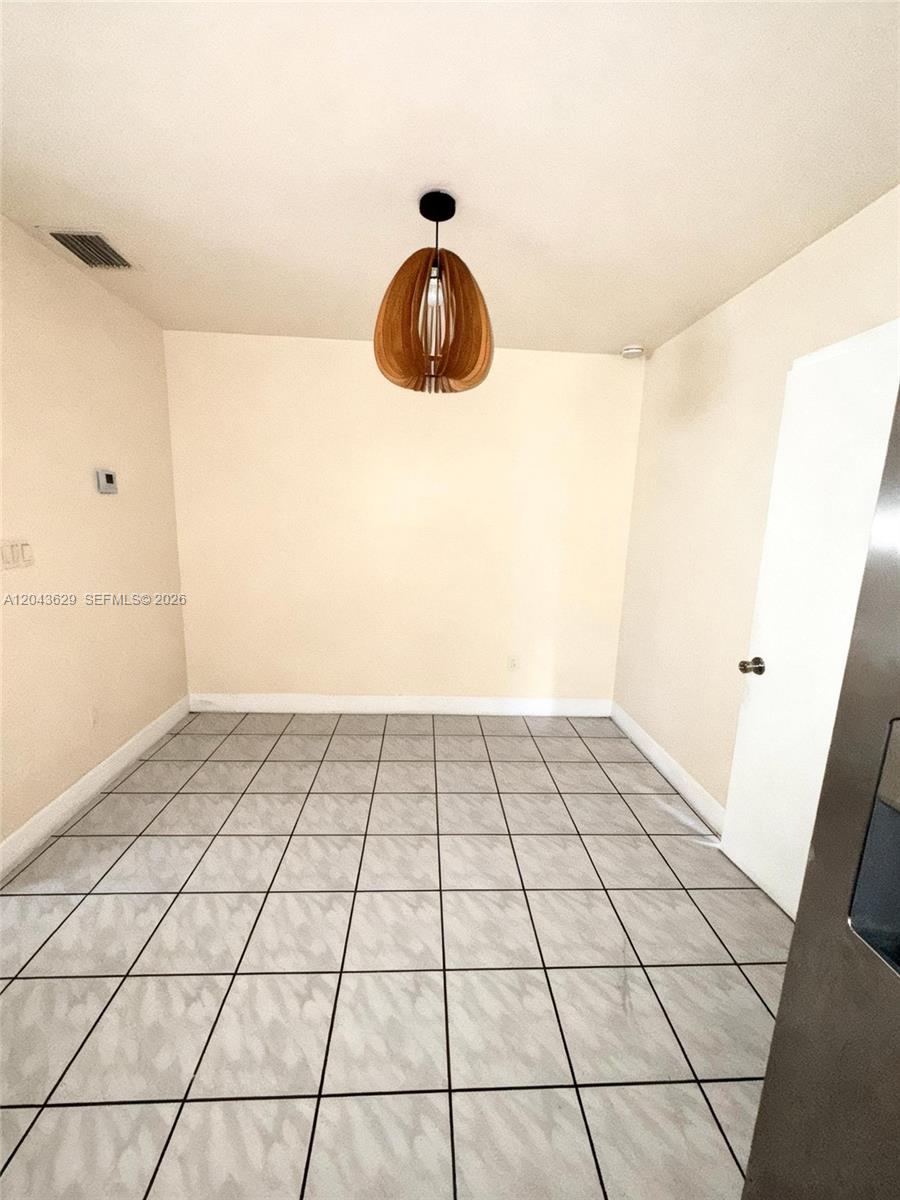 A dining area features light-colored tile flooring, cream walls, and a wooden pendant light fixture — 5912 Fillmore St # 2, Hollywood FL 33021, HOLLYWOOD, FL