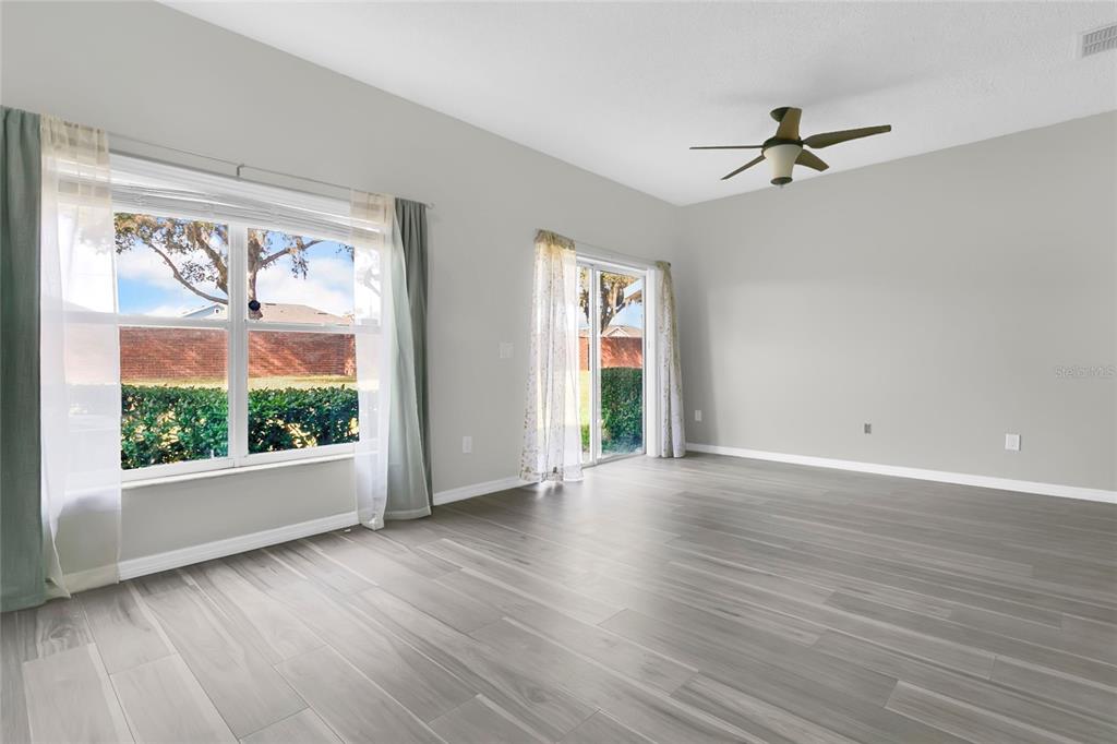An empty room with gray wood-look flooring, a ceiling fan, and sliding glass doors — 1748 FRITWELL COURT, OCOEE, FL