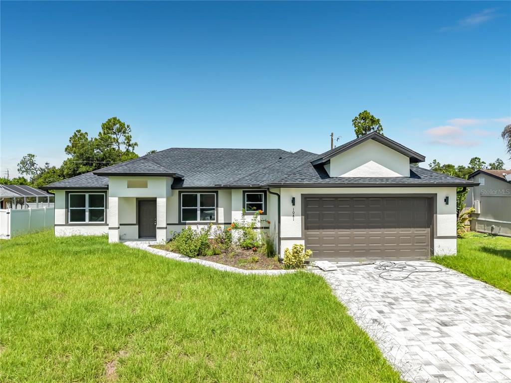 A single-story house with a white stucco exterior, dark roof, and a paved driveway — 1081 MCCRORY STREET, NORTH PORT, FL