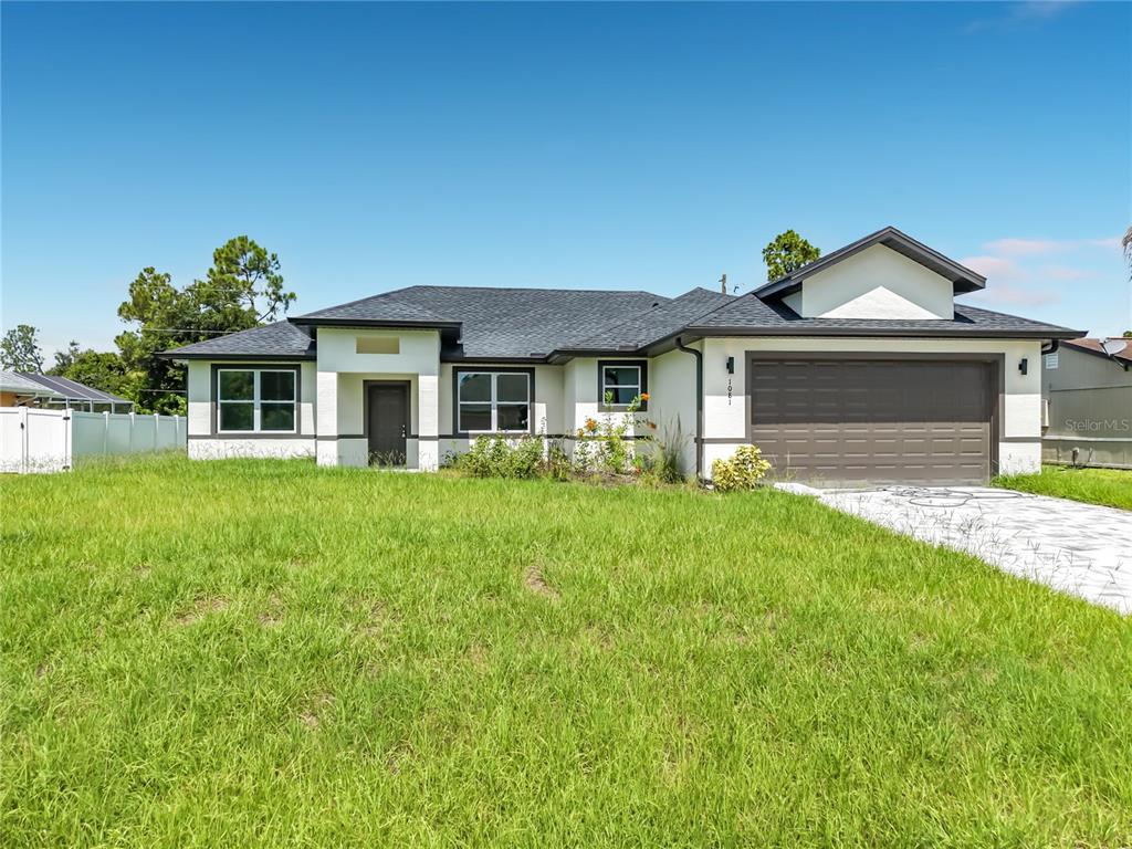 A single-story house with a white exterior, dark trim, and a two-car garage — 1081 MCCRORY STREET, NORTH PORT, FL