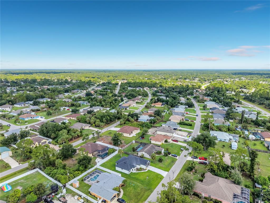 An aerial view shows a suburban neighborhood with single-family homes, green lawns, and paved streets — 1081 MCCRORY STREET, NORTH PORT, FL