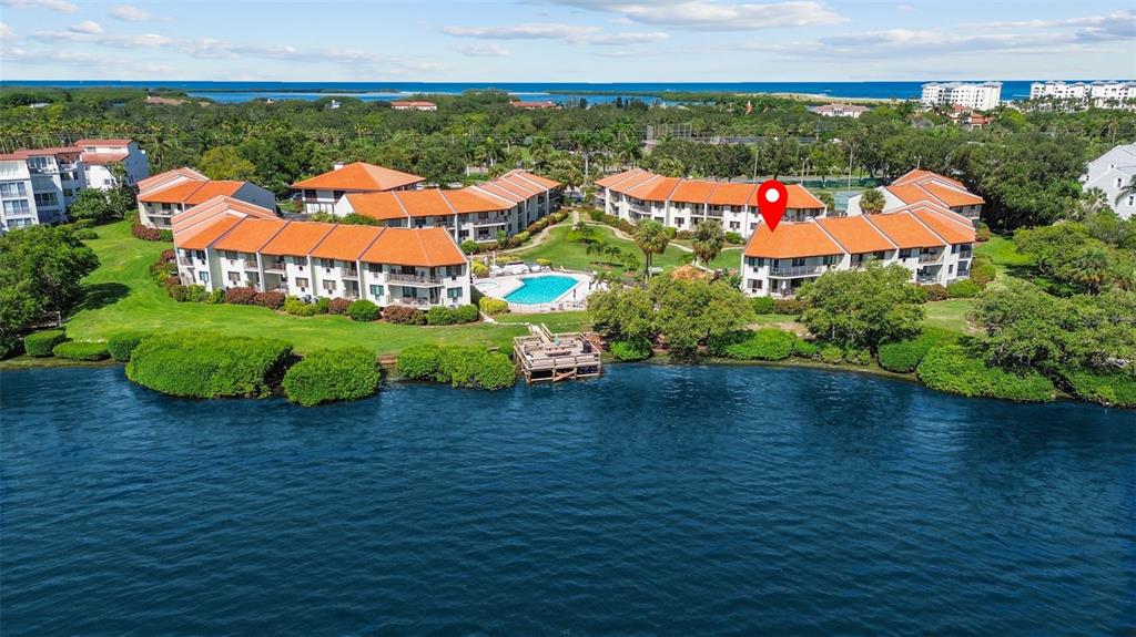 An aerial view shows waterfront condominium buildings with orange roofs surrounding a swimming pool — 1515 PINELLAS BAYWAY S UNIT 65, ST PETERSBURG, FL