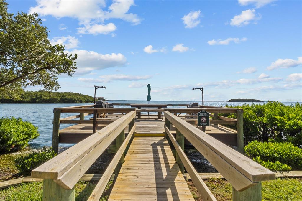 A wooden walkway leads to a deck overlooking a body of water with mangroves nearby — 1515 PINELLAS BAYWAY S UNIT 65, ST PETERSBURG, FL
