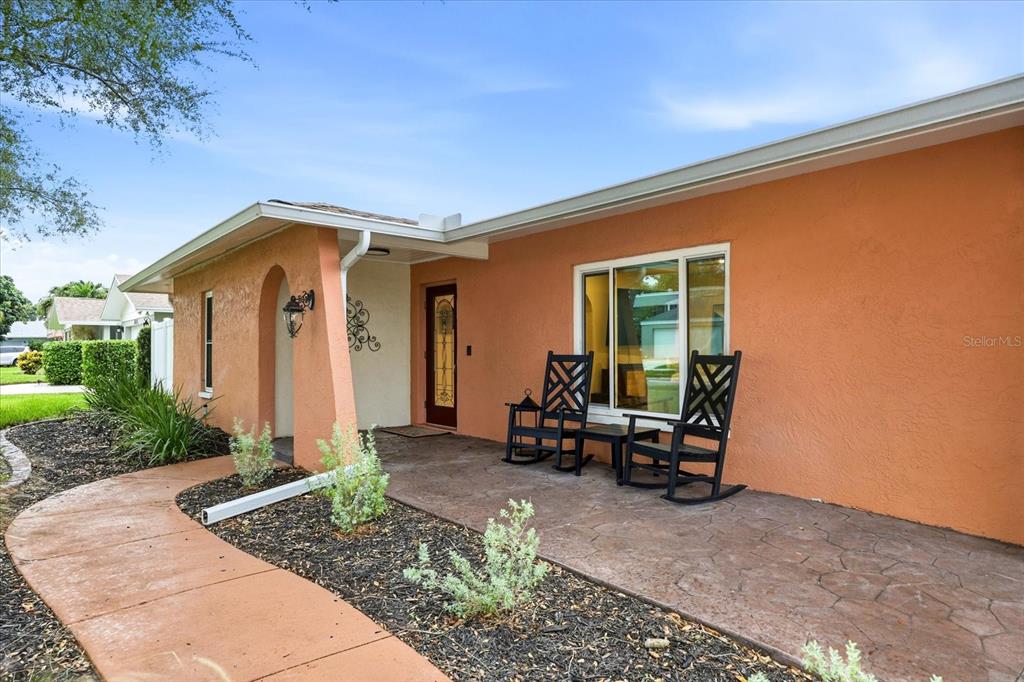 A peach-colored house exterior features a covered front porch with two black rocking chairs — 8805 KENWOOD ROAD, SEMINOLE, FL