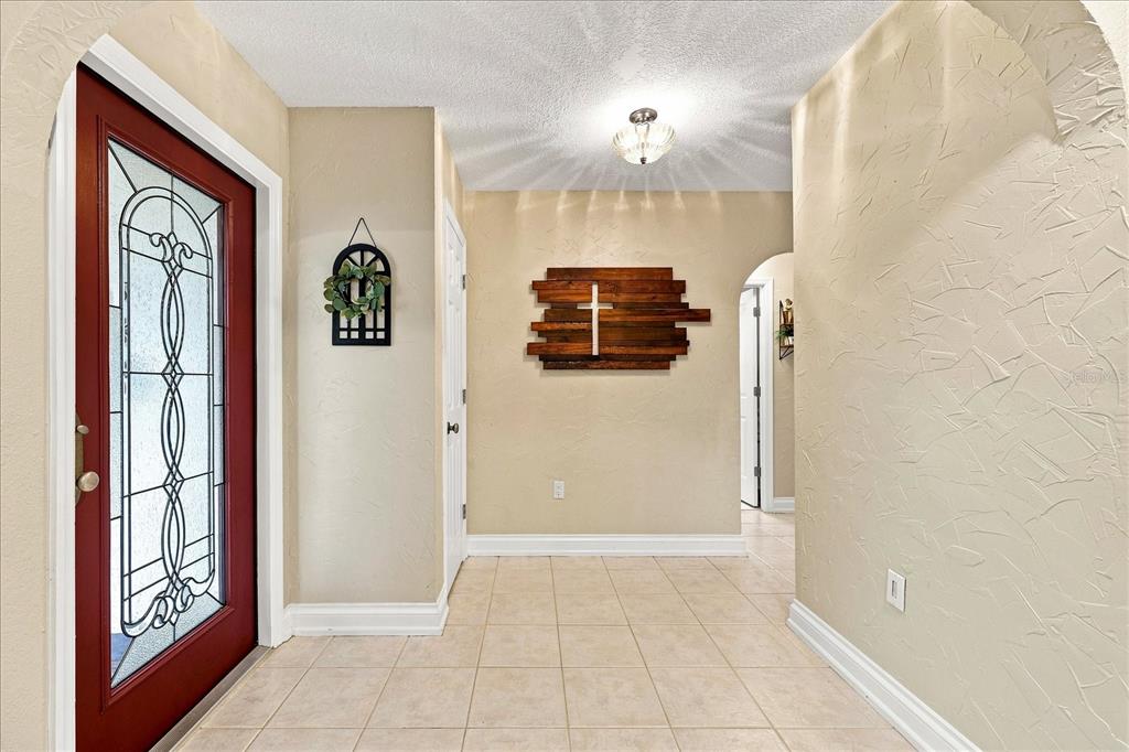 A tiled entryway features a red front door with glass panels and a wooden cross — 8805 KENWOOD ROAD, SEMINOLE, FL
