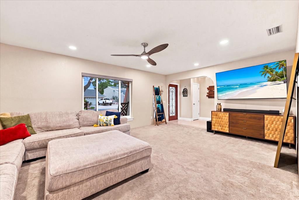 A living room features a large sectional sofa, a television, and a ceiling fan — 8805 KENWOOD ROAD, SEMINOLE, FL