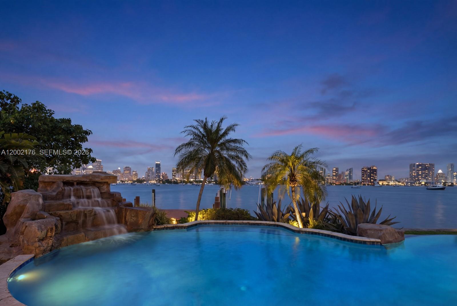 An infinity pool with a rock waterfall overlooks a bay and a city skyline — 432 S Hibiscus Dr, Miami Beach FL 33139, MIAMI BEACH, FL