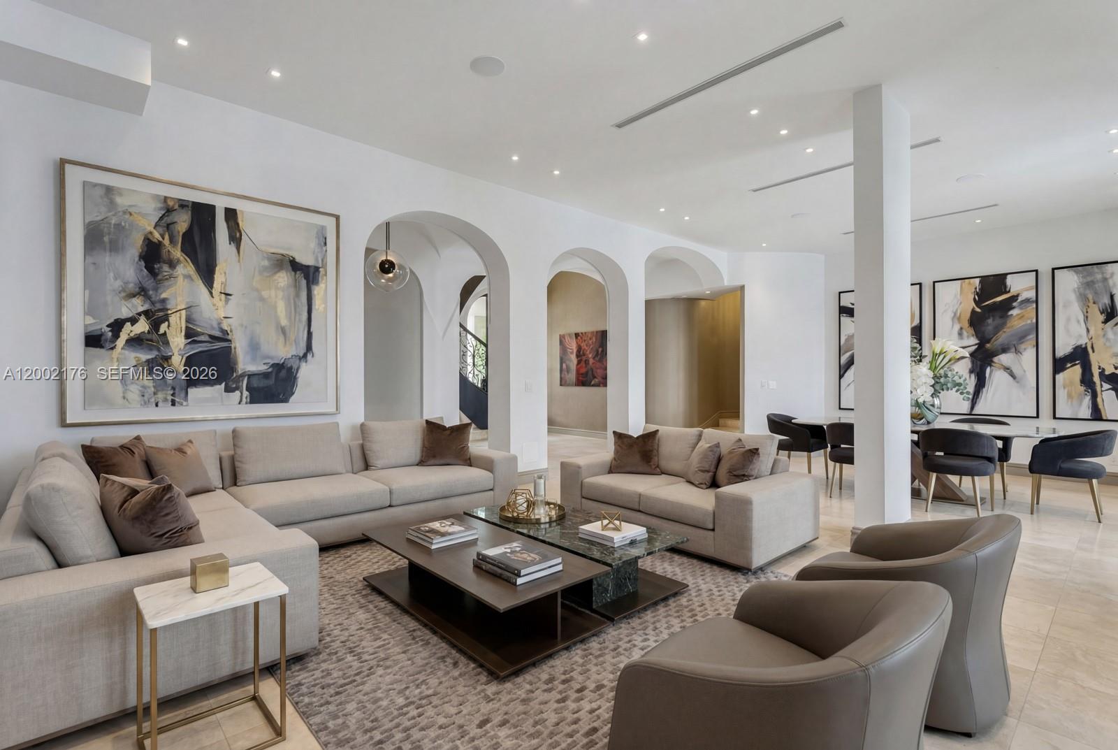 A spacious living room features neutral sofas, arched architectural details, and modern abstract wall art — 432 S Hibiscus Dr, Miami Beach FL 33139, MIAMI BEACH, FL