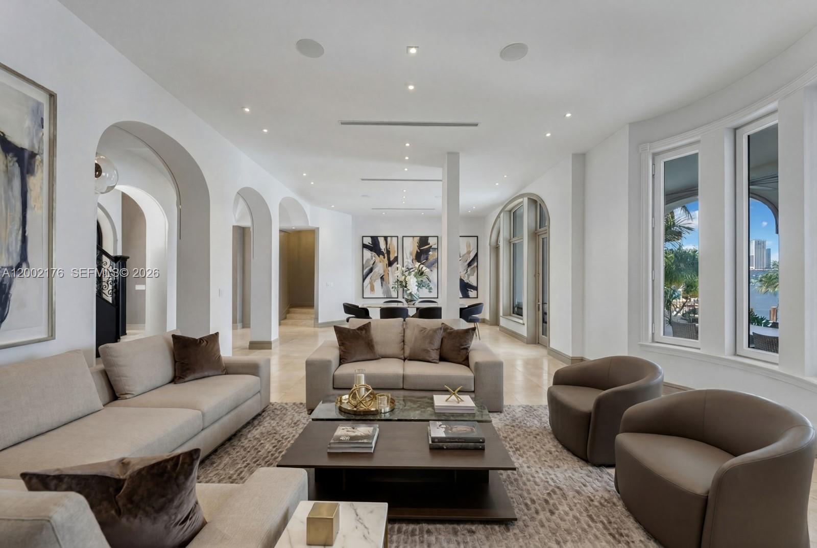 A bright living room features beige sofas, brown armchairs, a coffee table, and arched doorways — 432 S Hibiscus Dr, Miami Beach FL 33139, MIAMI BEACH, FL