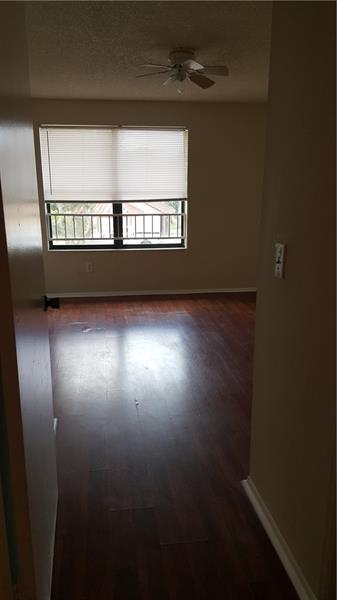An empty room with dark wood-look flooring, a ceiling fan, and a window with blinds — 4541 W Mcnab Road # 26, Pompano Beach FL 33069, POMPANO BEACH, FL