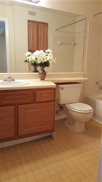 A bathroom features a wooden vanity with a white sink, a toilet, and a large mirror — 4541 W Mcnab Road # 26, Pompano Beach FL 33069, POMPANO BEACH, FL