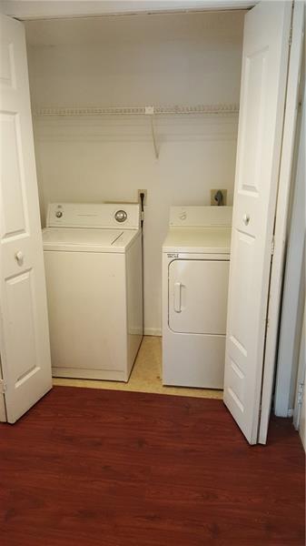 A laundry closet features a white top-load washer and dryer on a wood-look floor — 4541 W Mcnab Road # 26, Pompano Beach FL 33069, POMPANO BEACH, FL