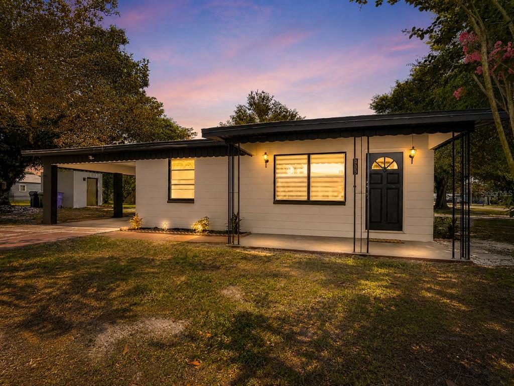 A single-story house with a white exterior, a black front door, and a covered carport — 438 CALIFORNIA AVENUE, ST CLOUD, FL