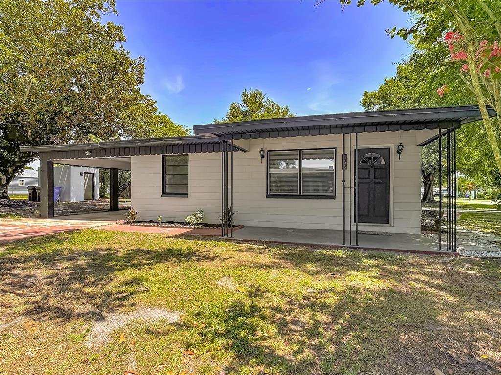 A single-story house with a white exterior, a covered front porch, and an attached carport — 438 CALIFORNIA AVENUE, ST CLOUD, FL