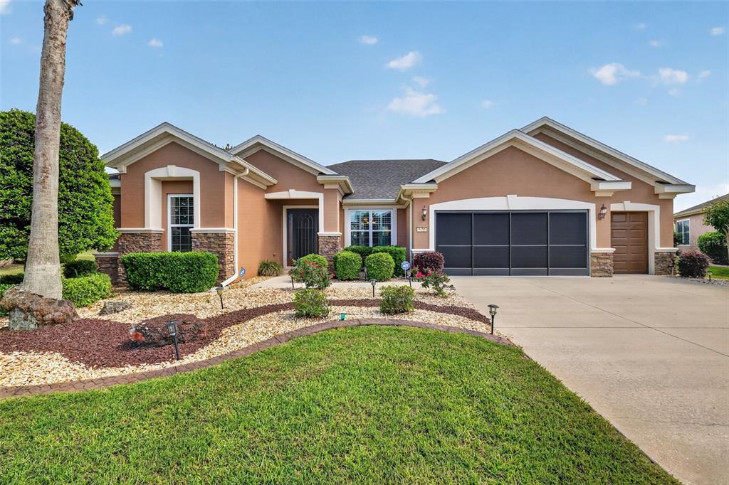 A single-story house with a tan stucco exterior, stone accents, and a three-car garage — 9455 SW 71ST LOOP, OCALA, FL