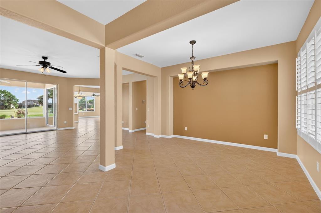 A dining room with tan walls, tile flooring, and a chandelier, opening to a living area — 9455 SW 71ST LOOP, OCALA, FL