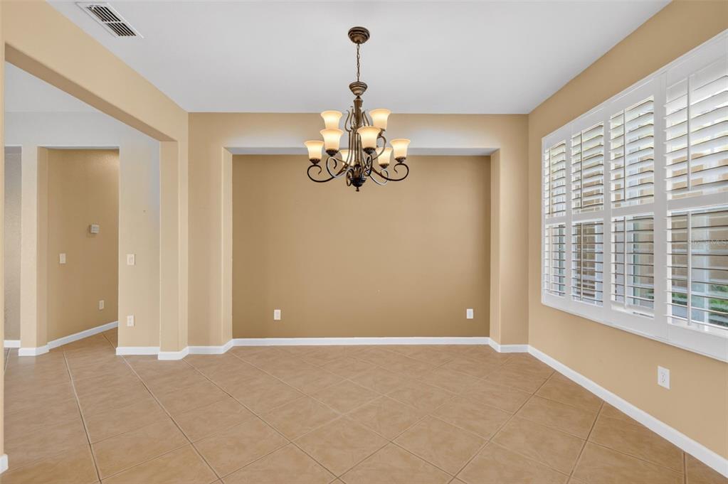 A dining room with tile flooring, a chandelier, and a recessed wall feature — 9455 SW 71ST LOOP, OCALA, FL