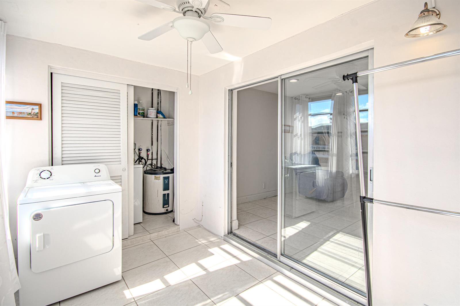 A laundry room with a white dryer, water heater closet, and sliding glass doors — 2222 NE 1st Way # 202, Boynton Beach FL 33435, BOYNTON BEACH, FL