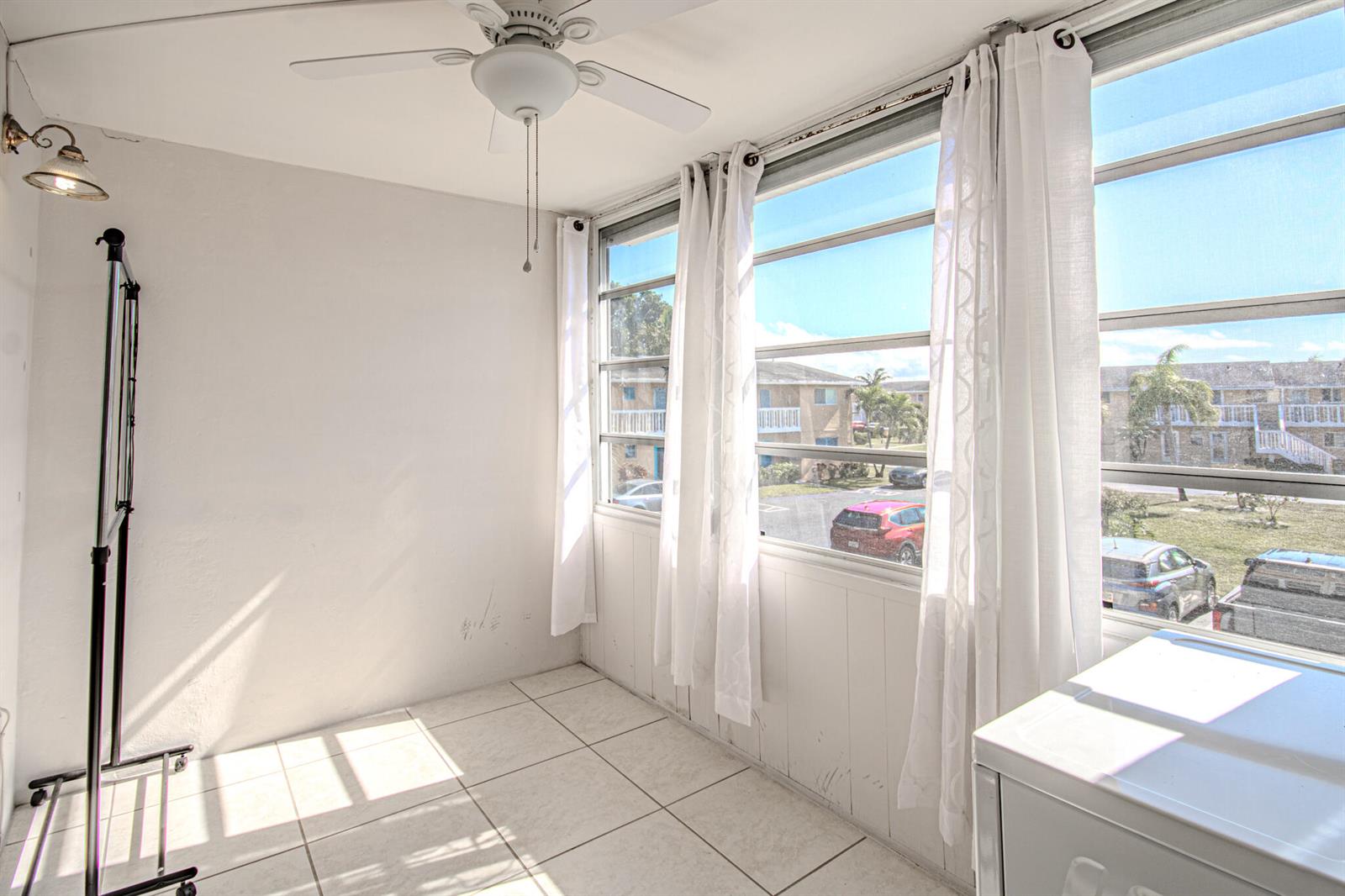 A sunroom with white tile floors, a ceiling fan, and large windows overlooking a parking lot — 2222 NE 1st Way # 202, Boynton Beach FL 33435, BOYNTON BEACH, FL