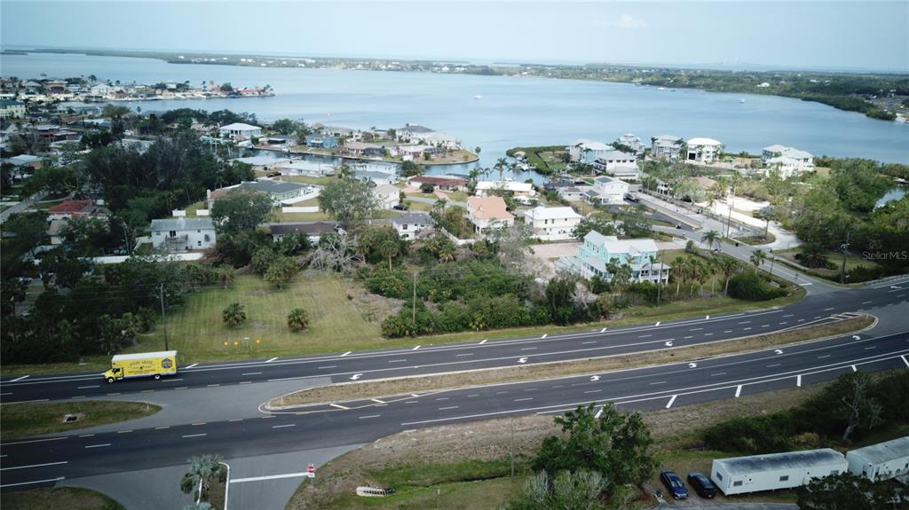 An aerial view shows a vacant lot situated between a multi-lane highway and waterfront homes — 5405 US HIGHWAY 19, PALMETTO, FL